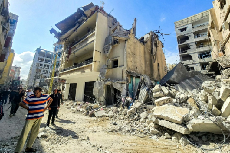 Des habitants devant les décombres de bâtiments endommagés et effondrés après des frappes israéliennes nocturnes sur la ville de Tyr, dans le sud du Liban, le 16 mai 2026 ( AFP / Kawnat HAJU )
