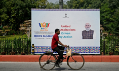 Un cycliste passe devant un panneau montrant le Premier ministre indien Narendra Modi, installé en amont du sommet des Brics, à New Delhi, le 9 septembre 2026 ( AFP / Sajjad HUSSAIN )