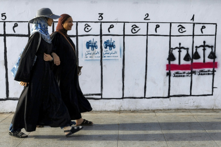 Des personnes passent devant des symboles utilisés par différents partis lors des élections législatives marocaines, à Rabat, le 14 septembre 2026 ( AFP / Abdel Majid BZIOUAT )