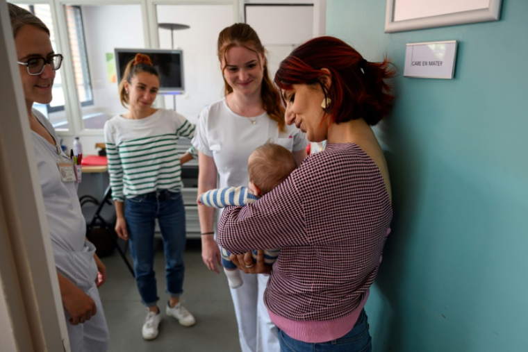 Cristina tient dans ses bras son fils Ezio aux côtés des personnels du service "Care en Mater" au centre hospitalier universitaire Purpan de Toulouse le 4 août 2025 ( AFP / Lionel BONAVENTURE )
