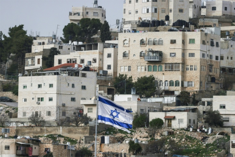 Un drapeau israélien flottant du dessus d'une colonie israélienne, devant des habitations palestiniennes d'Hébron, en Cisjordanie, le 9 février 2026 ( AFP / HAZEM BADER )