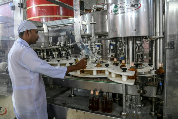Un employé de la distillerie Carew and Co. contrôle une ligne d'embouteillage, à Darsana, le 23 octobre 2025 dans le sud-ouest du Bangladesh ( AFP / Rehman ASAD )