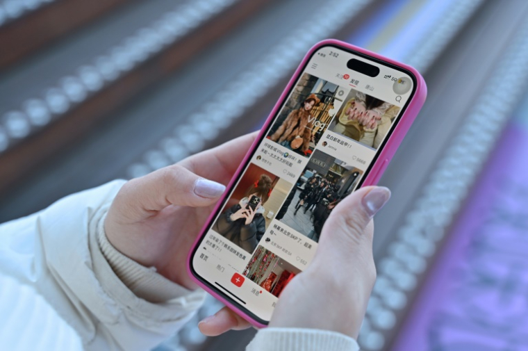 Une femme consulte sur son smartphone le réseau social chinois Xiaohongshu, également connu sous le nom de RedNote, le 15 janvier 2025 à Pékin ( AFP / ADEK BERRY )