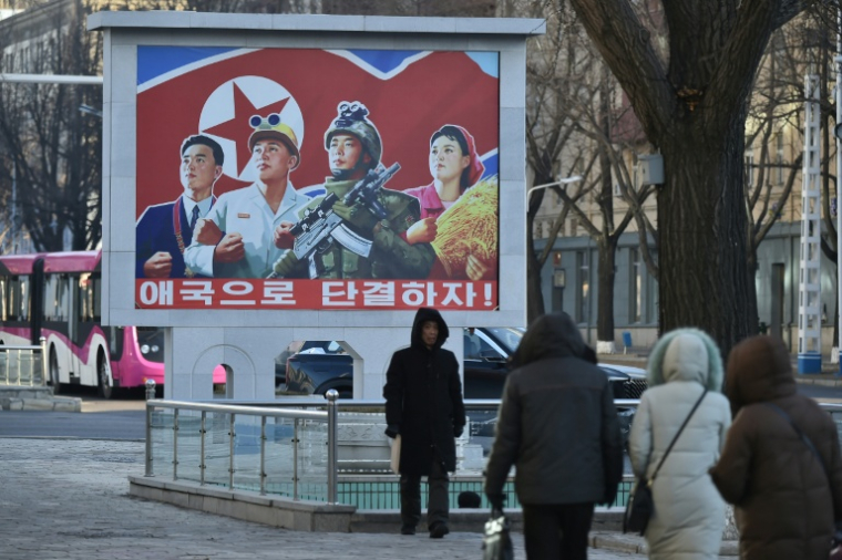 Des personnes marchent une rue de Pyongyang devant une affiche patriotique nord-coréenne, le 20 janvier 2026 ( AFP / KIM Won Jin )