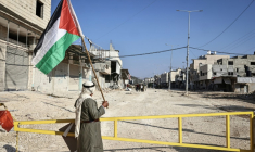 Un homme tenant un drapeau palestinien devant l'entrée du camp de réfugiés de Nur Shams, à coté de Tulkarem, le 18 novembre 2025 ( AFP / Zain JAAFAR )