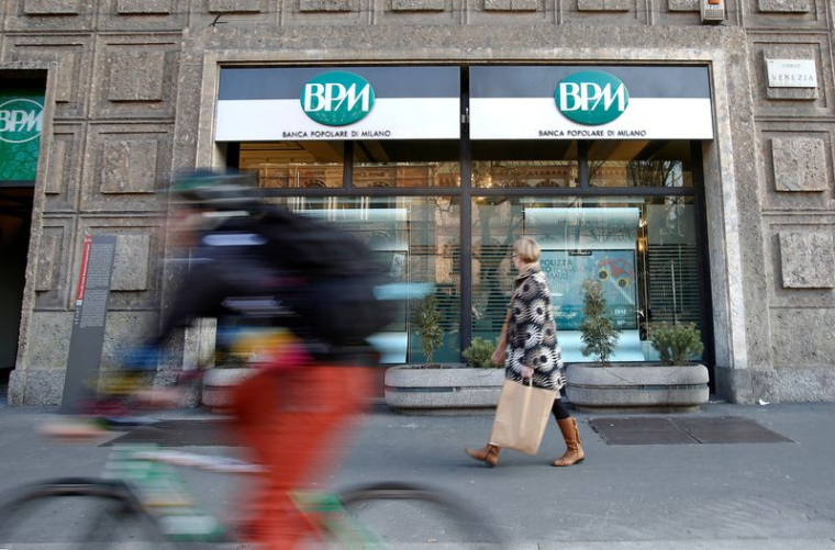 Une femme marche devant la Banca Popolare di Milano (BPM), dans le centre de Milan