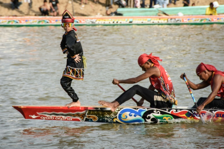 Rayyan Arkan Dikha danse à l'avant d'un bateau lors d'une course nautique traditionnelle, le 21 août 2025 sur la rivière Kuantan, dans la province indonésienne de Riau, sur l'île de Sumatra ( AFP / Wahyudi )