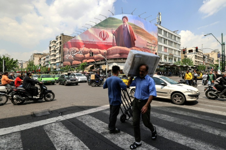 Des passants marchent devant un grand panneau représentant le guide suprême iranien Mojtaba Khamenei, le 20 avril 2026 à Téhéran ( AFP / ATTA KENARE )