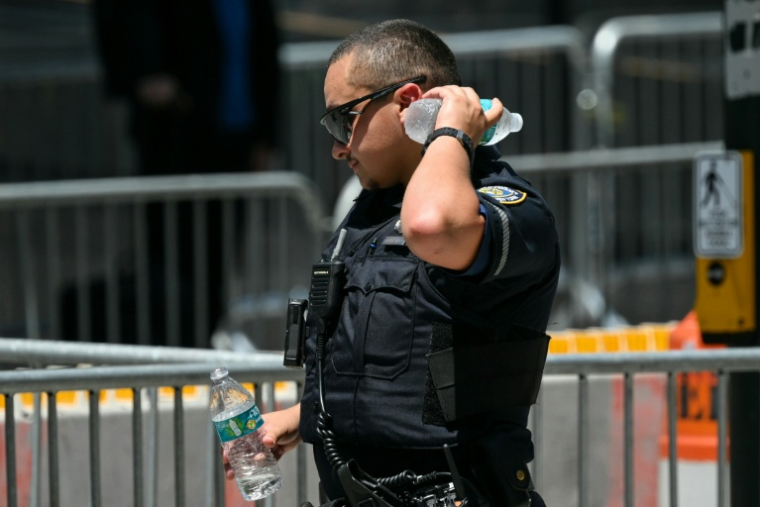 Un policier se rafraichit avec une bouteille d'eau lors d'une vague de chaleur le 3 juillet 2026 à New York ( AFP / ANGELA WEISS )