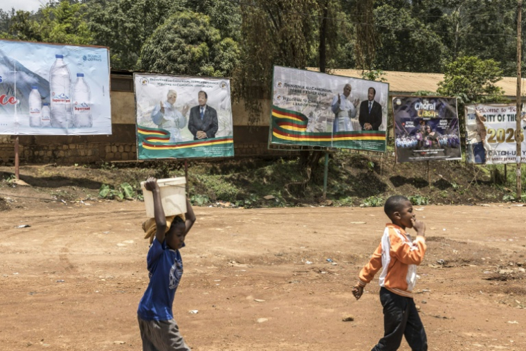 Des enfants passent devant des affiches montrant le pape Léon XIV et le président camerounais Paul Biya, à Bamenda, le 13 avril 2026, à la veille de la visite du pape au Cameroun ( AFP / PATRICK MEINHARDT )