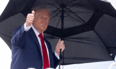 Le président américain Donald Trump tient un parapluie et lève le pouce alors qu'il monte à bord d'Air Force One avant son départ de la base aérienne d'Andrews, près de Washington, le 12 octobre 2025 ( AFP / SAUL LOEB )