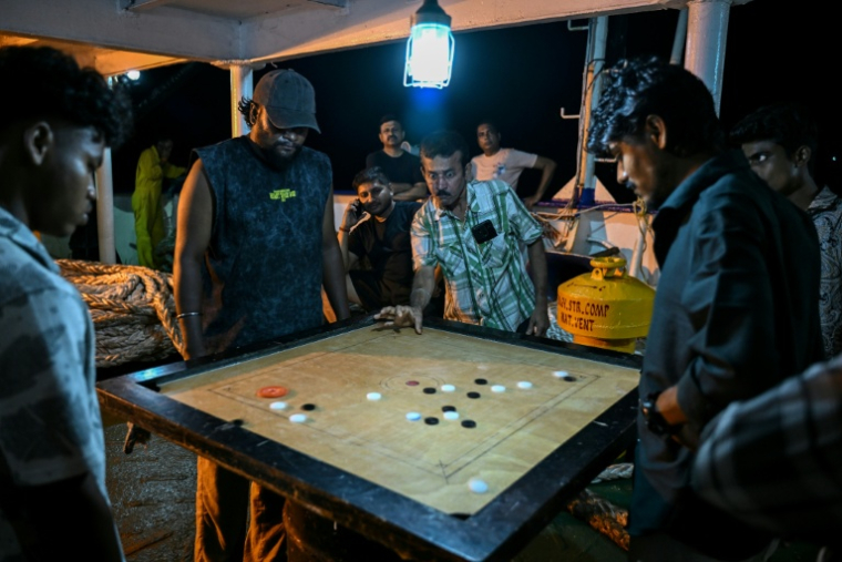 Des passagers jouent au carom à bord du ferry Kalighat, l'unique lien entre Chowra et Car Nicobar, deux minuscules morceaux de l'archipel indien des Andaman-et-Nicobar, en plein cœur de l'océan Indien, le 30 mars 2026 ( AFP / R. Satish BABU )