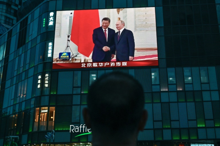 Les présidents russe Vladimir Poutine (d) et chinois Xi Jinping à Moscou sur un écran posé contre la façade d'un centre commercial à Pékin, le 8 mai 2025 ( AFP / Pedro PARDO )