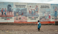 Un enfant revenant de l’école s’arrête pour regarder des panneaux de sensibilisation à Ebola du Centre de traitement Ebola (CTE) de Munigi, le 2 juin 2026 ( AFP / Jospin Mwisha )