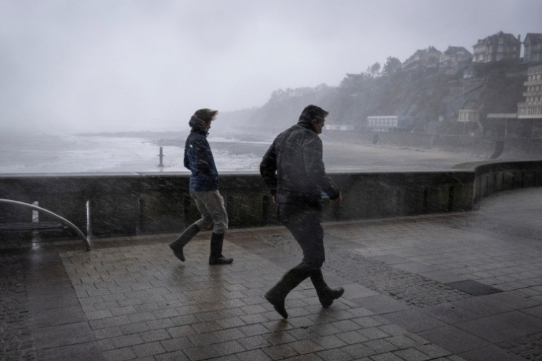 Des promeneurs pris dans les bourrasques de la tempête Austen sur le front de mer à Granville, dans la Manche, le 23 octobre 2026 ( AFP / Guillaume SALIGOT )
