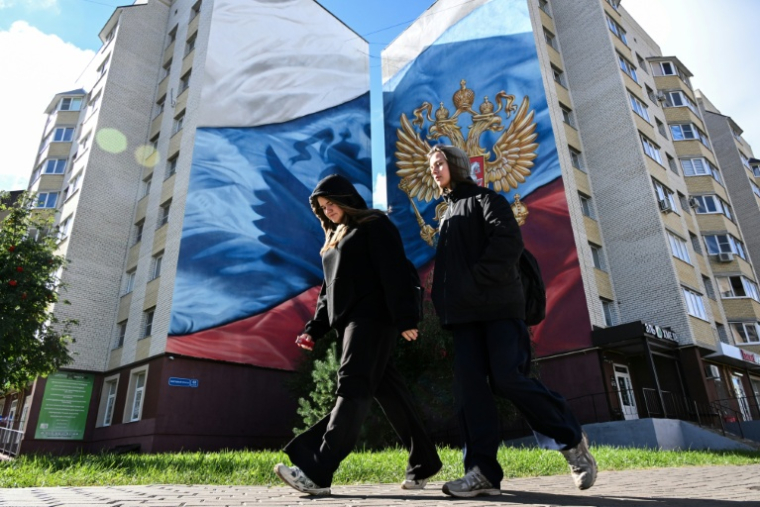 Des jeunes devant une fresque peinte en 2023 représentant le drapeau et le blason russe, à Tambov, le 9 septembre 2026 ( AFP / Igor IVANKO )