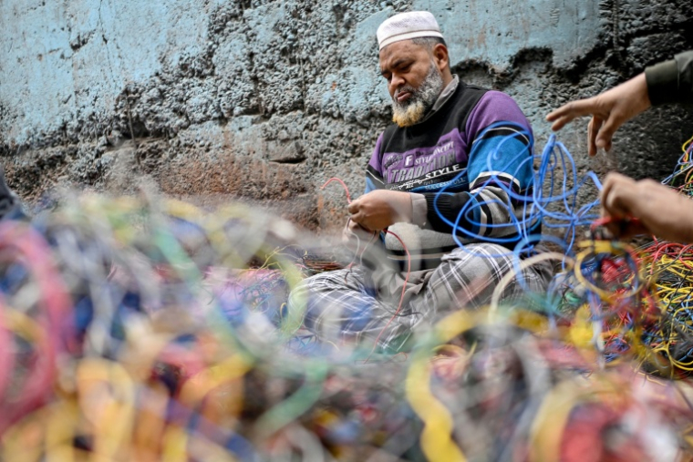 Un homme récupérant le cuivre provenant de déchets de fils électriques dans un site informel de recyclage de déchets électroniques à Seelampur, New Delhi, le 28 janvier 2026 ( AFP / Arun SANKAR )
