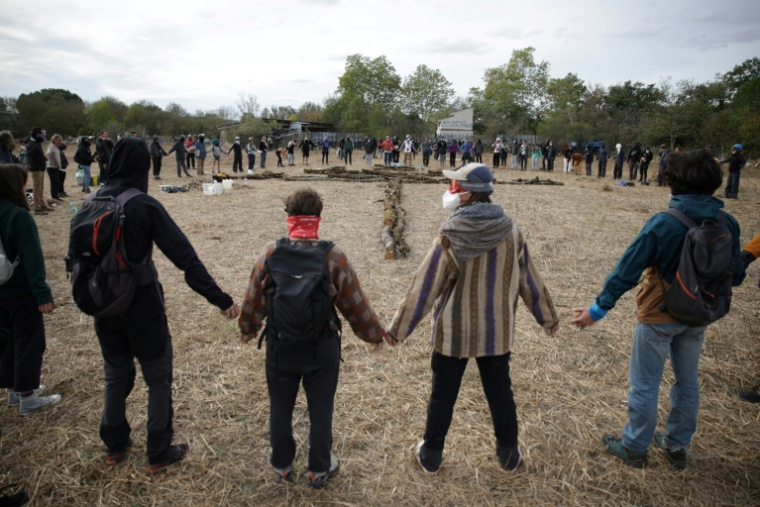 Des membres des "Soulevements de la Terre" font une ronde autour de troncs après une opération d'évacuation du campement de la ZAD (Zone à Défendre) destiné à protester contre le projet d'autoroute A69 entre Toulouse et Castres, le 22 octobre 2023 3à Saïx, dans le Tarn . ( AFP / Valentine CHAPUIS )