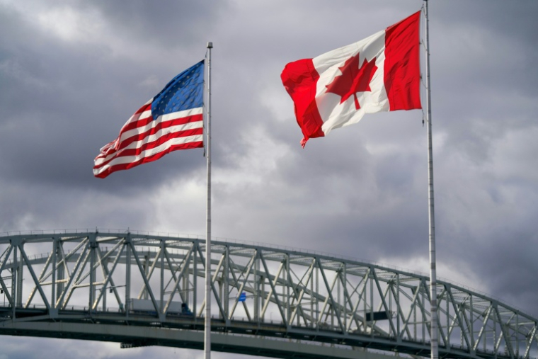 Les drapeaux américain et canadien près du poste frontalier du pont Blue Water à Point Edward, en Ontario, le 24 octobre 2025 au Canada ( AFP / Geoff Robins )