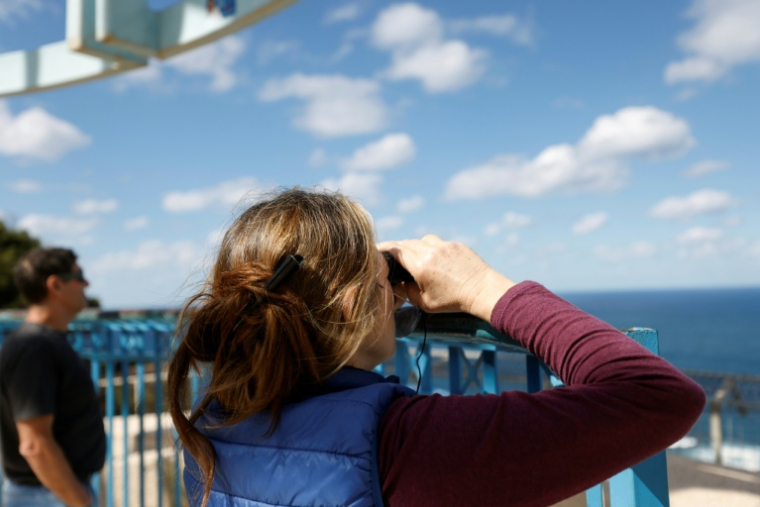 Des Israéliens regardent en direction de la mer Méditerranée, dans l'attente de l'arrivée du porte-avions américain Gerald Ford, à Haïfa dans le nord d'Israël, le 27 février 2026 ( AFP / Jalaa MAREY )