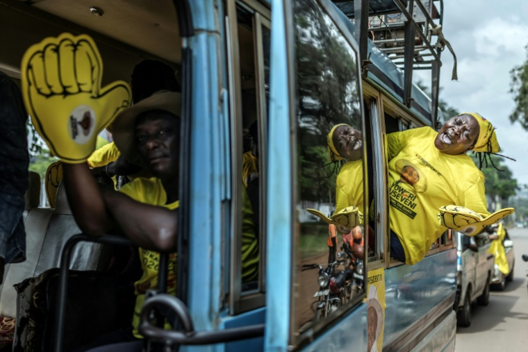 Des partisans du président ougandais sortant et candidat à sa réélection Yoweri Museveni chantent des slogans dans un bus se rendant au dernier meeting de campagne du parti au pouvoir avant la présidentielle et les législatives, le 13 janvier 2026 à Kampala ( AFP / - )