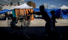 Des enfants jouent près de tentes installées sur le parvis du siège du Samusocial, occupé par des familles et des personnes en attente d'un hébergement d'urgence, à Paris, le 1er août 2026 ( AFP / Simon WOHLFAHRT )
