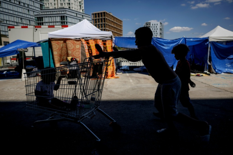 Des enfants jouent près de tentes installées sur le parvis du siège du Samusocial, occupé par des familles et des personnes en attente d'un hébergement d'urgence, à Paris, le 1er août 2026 ( AFP / Simon WOHLFAHRT )