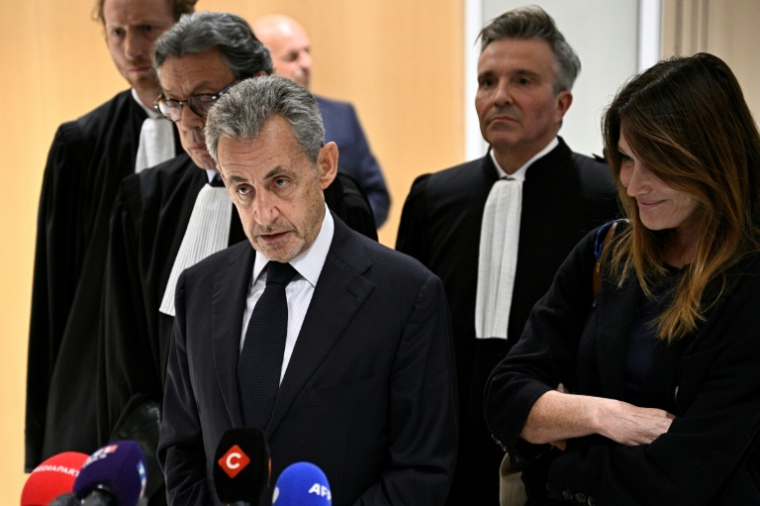 L'ex-président Nicolas Sarkozy (au centre) parle à la presse, accompagné de son épouse Carla Bruni (à droite) et de l'avocat Jean-Michel Darrois (deuxième à gauche) au tribunal à Paris, le 25 septembre 2025 ( AFP / JULIEN DE ROSA )