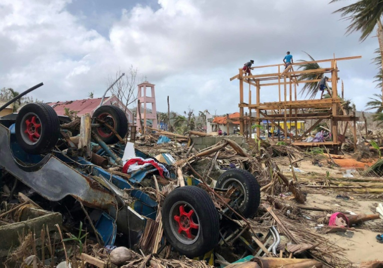 Des habitants reconstruisent une maison après le passage du typhon Rai en décembre 2021, le 3 janvier 2022 à Burgos, sur l'île de Siargao, aux Philippines ( AFP / Roel CATOTO )
