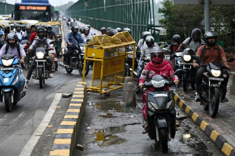 Des motocyclistes roulent sur un trottoir pour piétons le long d'un pont à New Delhi, le 8 juillet 2026 en Inde ( AFP / Arun SANKAR )