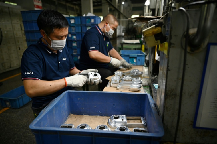 Des ouvriers dans une usine du groupe taïwanais LCM, produisant des pièces automobiles, accessoires ménagers et serrures de porte intelligentes, à Kunshan, dans la province orientale du Jiangsu, le 10 juin 2025 en Chine ( AFP / GREG BAKER )