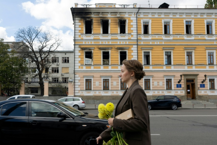 Une femme marche le 5 octobre 2026 devant le bâtiment de l'Académie nationale des sciences à Kiev endommagé par une frappe russe ( AFP / Tetiana DZHAFAROVA )