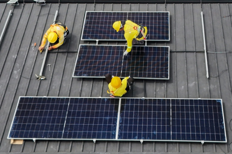Vue aérienne montrant des ouvriers qui installent des panneaux solaires sur un toit à Carmona, aux Philippines, le 9 juillet 2026 ( AFP / Jam STA ROSA )