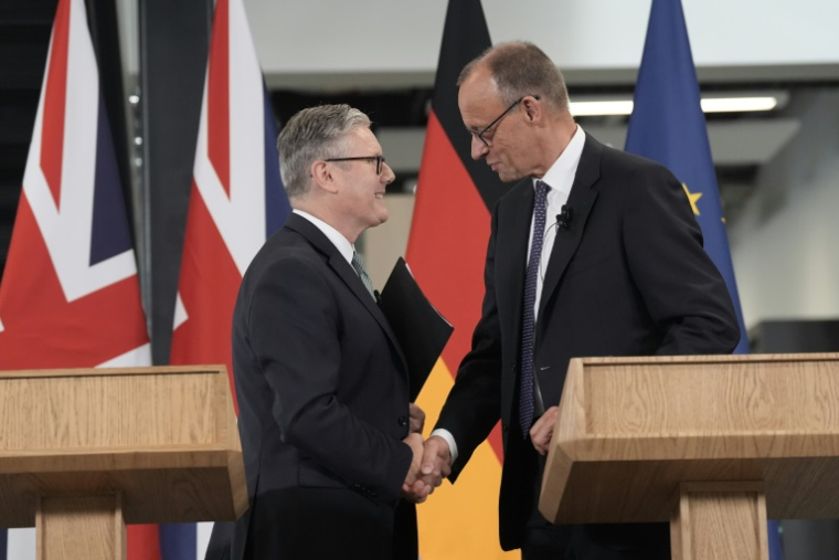 Le Premier ministre britannique Keir Starmer (g) et le chancelier allemand Friedrich Merz se serrent la main après avoir prononcé un discours lors de leur visite de l'usine Airbus à Stevenage, dans le sud de l'Angleterre, le 17 juillet 2025 ( POOL / Stefan Rousseau )