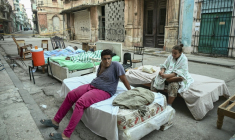 Plusieurs familles passent la nuit sur des lits installés dans la rue, dans un quartier central de La Havane, le 30 juillet 2026, après l'effondrement partiel de leur immeuble ( AFP / YAMIL LAGE )