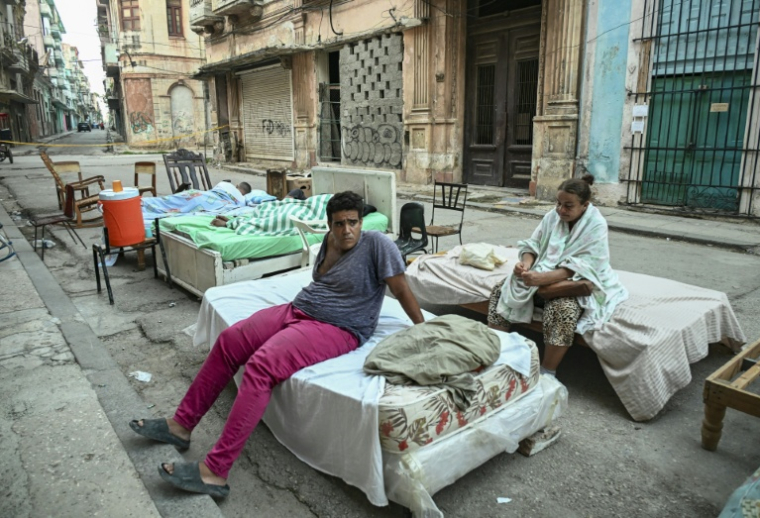 Plusieurs familles passent la nuit sur des lits installés dans la rue, dans un quartier central de La Havane, le 30 juillet 2026, après l'effondrement partiel de leur immeuble ( AFP / YAMIL LAGE )