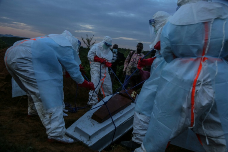 Du personnel médical en combinaison de protection enterre un patient décédé à Rwampara le 21 mai 2026 en République démocratique du Congo ( AFP / Seros MUYISA )