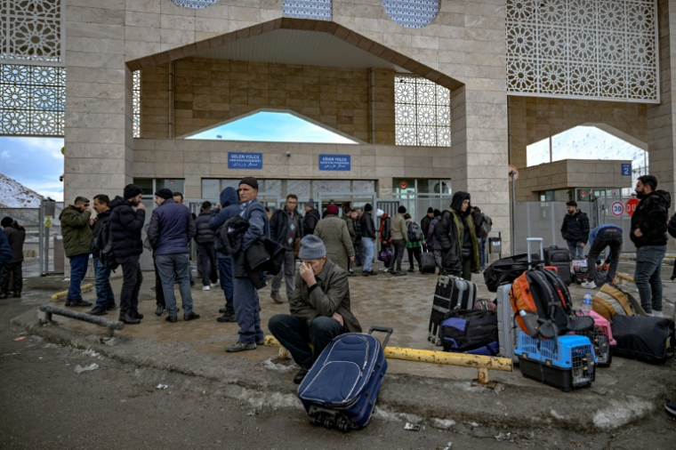 Des Iraniens attendent des bus après avoir franchi le principal poste-frontière de Razi-Kapiköy entre l'Iran et la Turquie, le 31 janvier 2026 ( AFP / Ozan KOSE )
