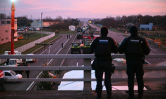Des gendarmes observent les agriculteurs sur l'autoroute A64 lors d'un blocage pour protester contre l'abattage obligatoire des troupeaux de bovins atteints de dermatose nodulaire contagieuse et l'accord  UE-Mercosur, à Carbonne, le 13 janvier 2026 en Haute-Garonne ( AFP / Lionel BONAVENTURE )