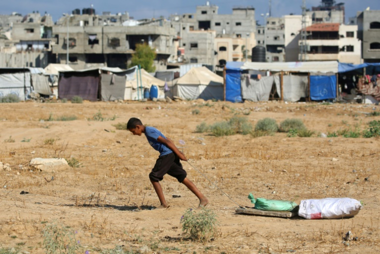 Un jeune Palestiniens tire des sacs récupérés dans une décharge au camp d'Al-Bureij, dans le centre de la bande de Gaza, le 7 juillet 2025 ( AFP / Eyad BABA )