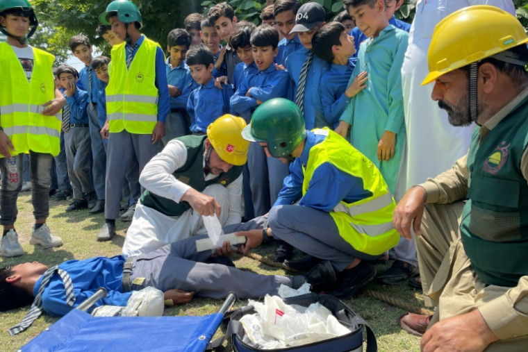 Des formateurs de la Défense civile donnent un cours de premiers secours à des écoliers dans une école à Muzaffarabad, au Cachemire pakistanais, où l'on craint un retour des hostilités avec l'Inde, le 30 avril 2025 ( AFP / Sajjad QAYYUM )