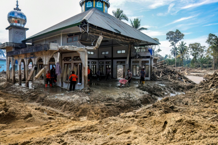 Des villageois tentent de nettoyer leur mosquée endommagée par les inondations à Aek Garoga dans le nord de l'île indonésienne de Sumatra, le 4 décembre 2025 ( AFP / AHMAD RIDWAN NASUTION )