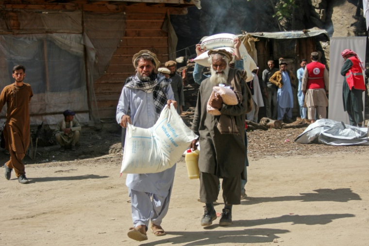 Des hommes transportent de l'aide alimentaire distribuée par le Comité international de la Croix-Rouge (CICR) à Kamdesh, dans la province de Nuristan, le 22 avril 2026 en Afghanistan ( AFP / Aimal ZAHIR )