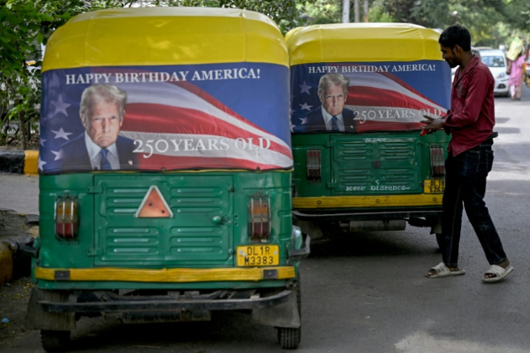 Un homme accroche une banderole à l'effigie de Donald Trump sur un triporteur à New Delhi, le 21 mai 2026 ( AFP / Arun SANKAR )