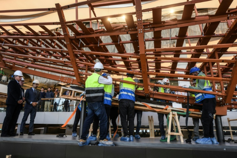 Des employés installent des planches de bois anciennes provenant de la deuxième barque du roi Khéops sur une structure métallique au Grand Musée égyptien de Gizeh, en périphérie du Caire, le 23 décembre 2025 ( AFP / Ahmed HASAN )