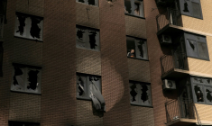 Un homme à travers une vitre brisée à l'intérieur d'un immeuble résidentiel endommagé par des frappes russes, à Kiev en Ukraine le 14 mai 2026 ( AFP / Roman PILIPEY )