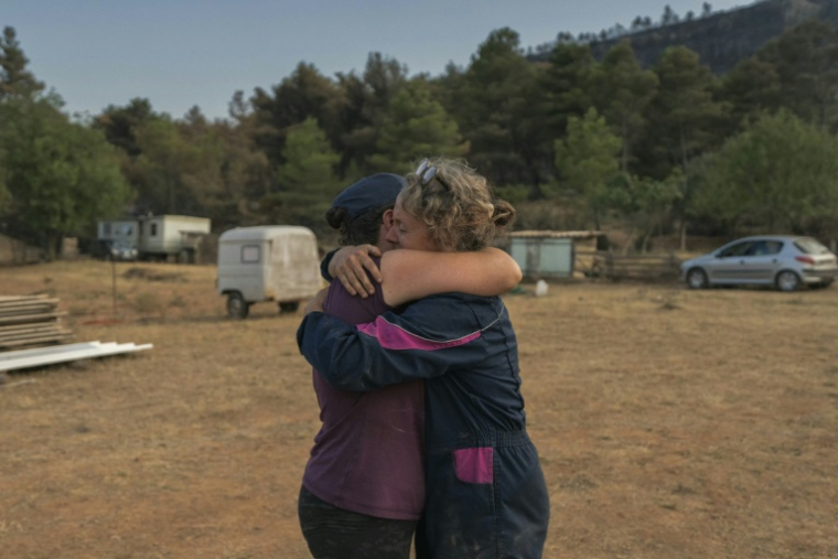 Emmanuelle Bernier pleure dans les bras de son amie alors que ses brebis sont évacuées suite à l'incendie de sa ferme à Fontjoncouse, le 9 août ( AFP / Idriss Bigou-Gilles )