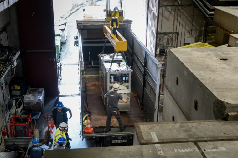Un dispositif cryogénique portable, rempli d'un nuage de 92 antiprotons, est transféré sur un camion, lors d'un essai réussi du premier système de transport d'antimatière au monde par la route, sur le campus du Cern, à Meyrin, près de Genève, le 24 mars 2026 en Suisse ( AFP / Fabrice COFFRINI )