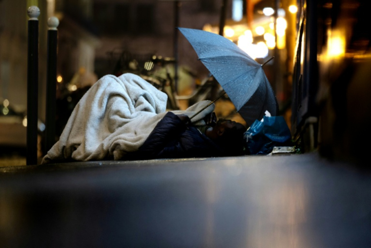 Un sans-abri dort sous la pluie dans une rue de Paris, le 30 janvier 2026 ( AFP / JOEL SAGET )