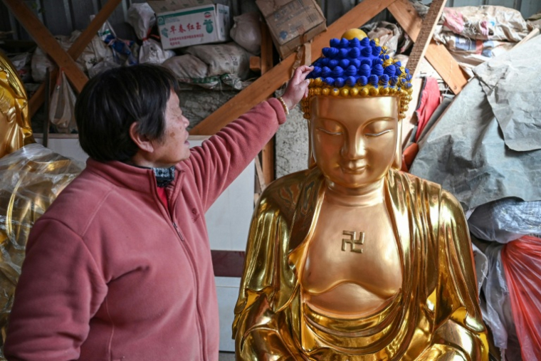 Sur cette photo prise le 16 janvier 2026, Gu, âgée de 71 ans, examine une sculpture bouddhique après un travail de dorure dans un atelier du village de Chongshan, à Suzhou, dans l'est de la Chine ( AFP / Jade GAO )